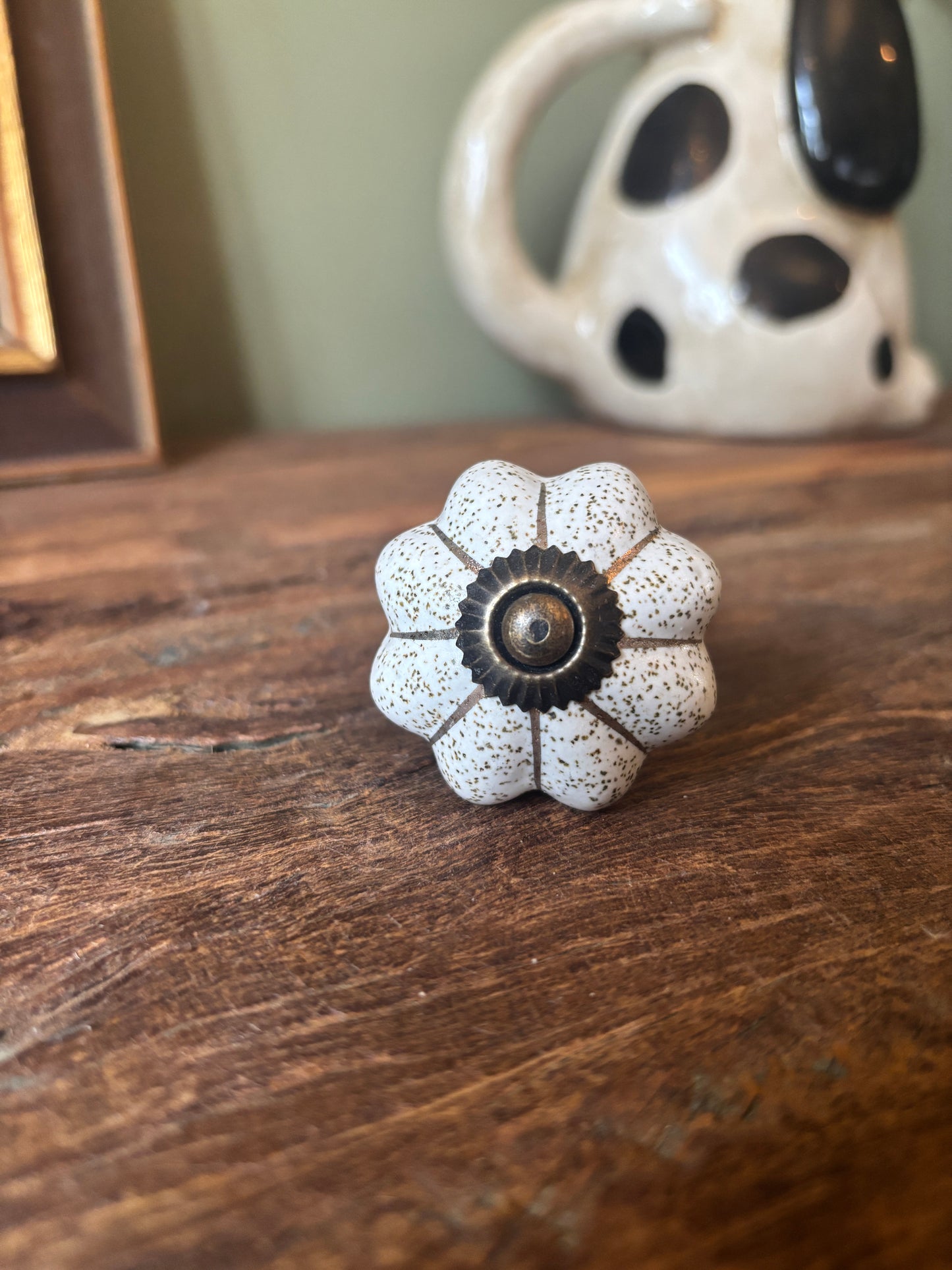 Decorative flower-shaped knob on a wooden surface with a ceramic pot in the background.