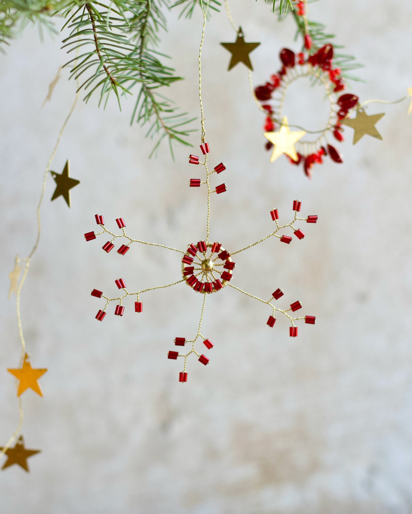 Decorative string with red and gold stars hanging against a neutral background