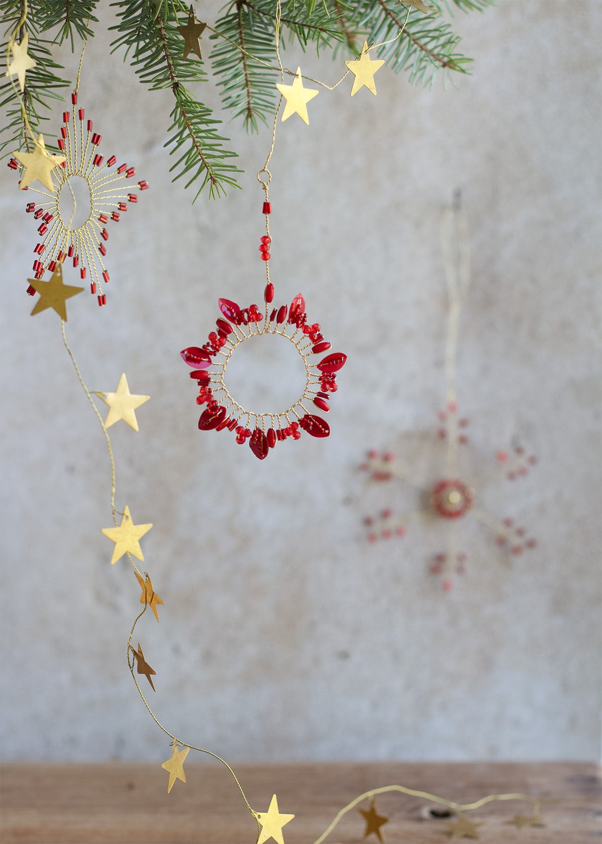 Decorative string lights with red bead accents and gold stars on a neutral background