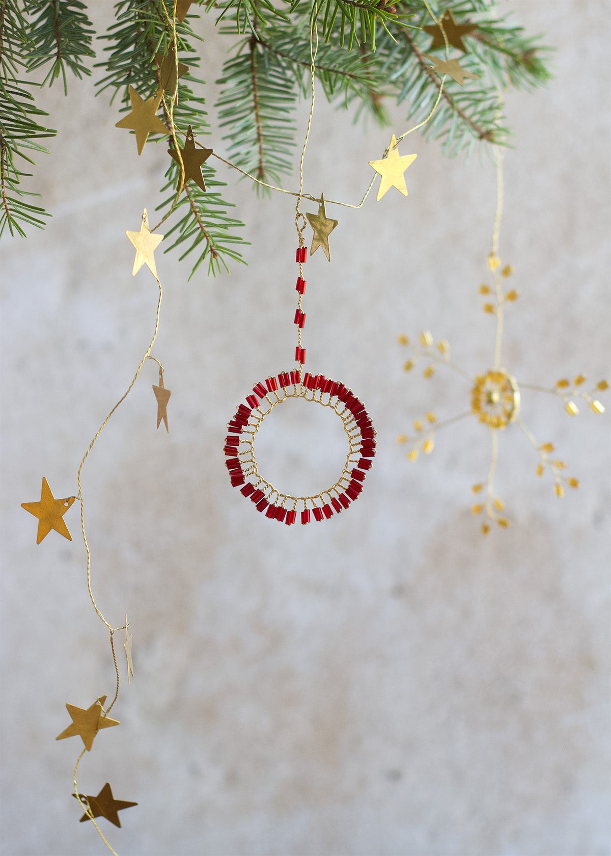 Decorative Christmas ornament with red beads and gold stars on a light background