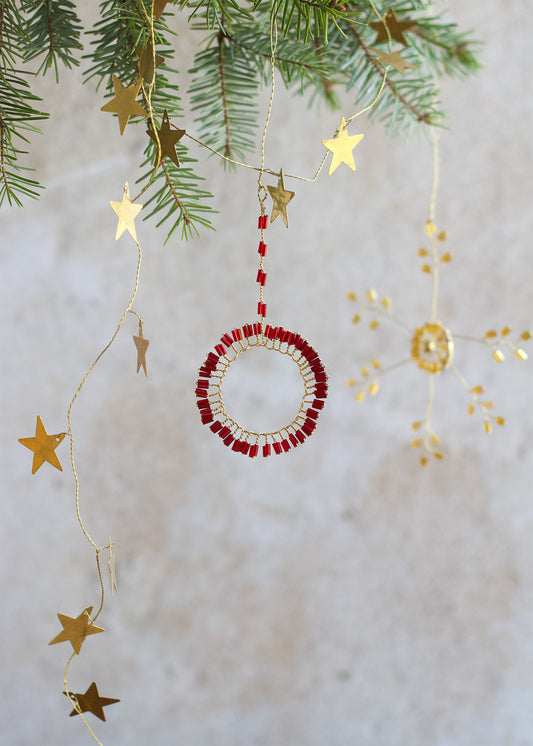 Decorative Christmas ornament with red beads and gold stars on a light background