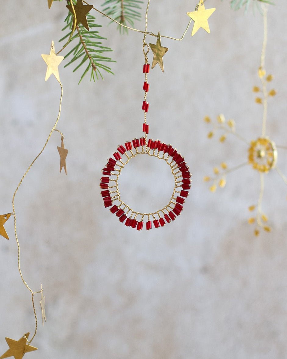 Decorative Christmas ornament with red beads and gold stars on a light background