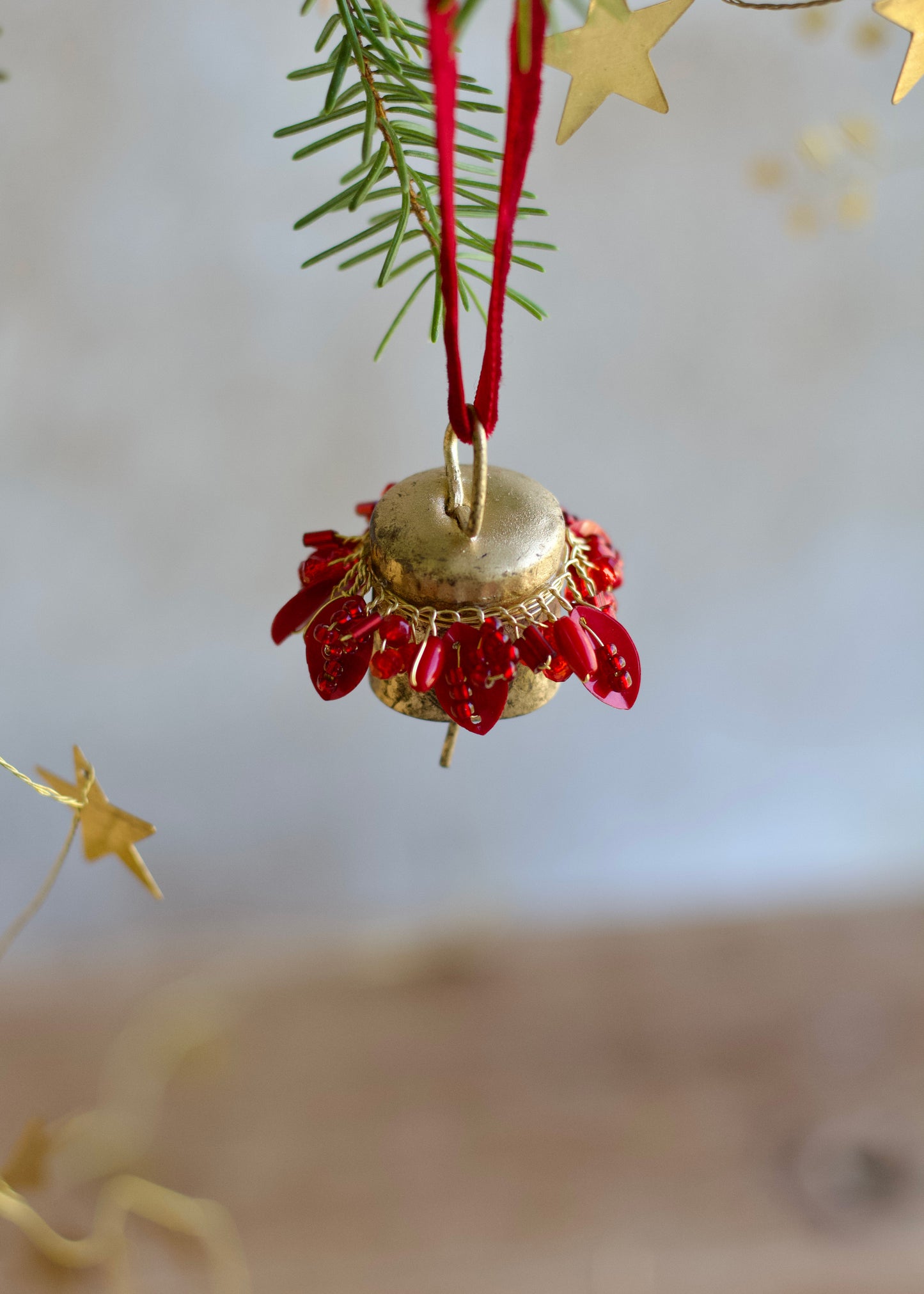 Gold bell ornament with red berries hanging from a branch with a blurred starry background