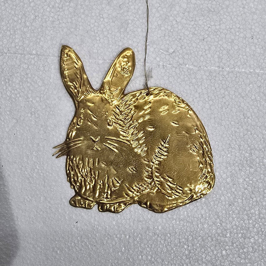 Gold rabbit-shaped ornament on a textured white background