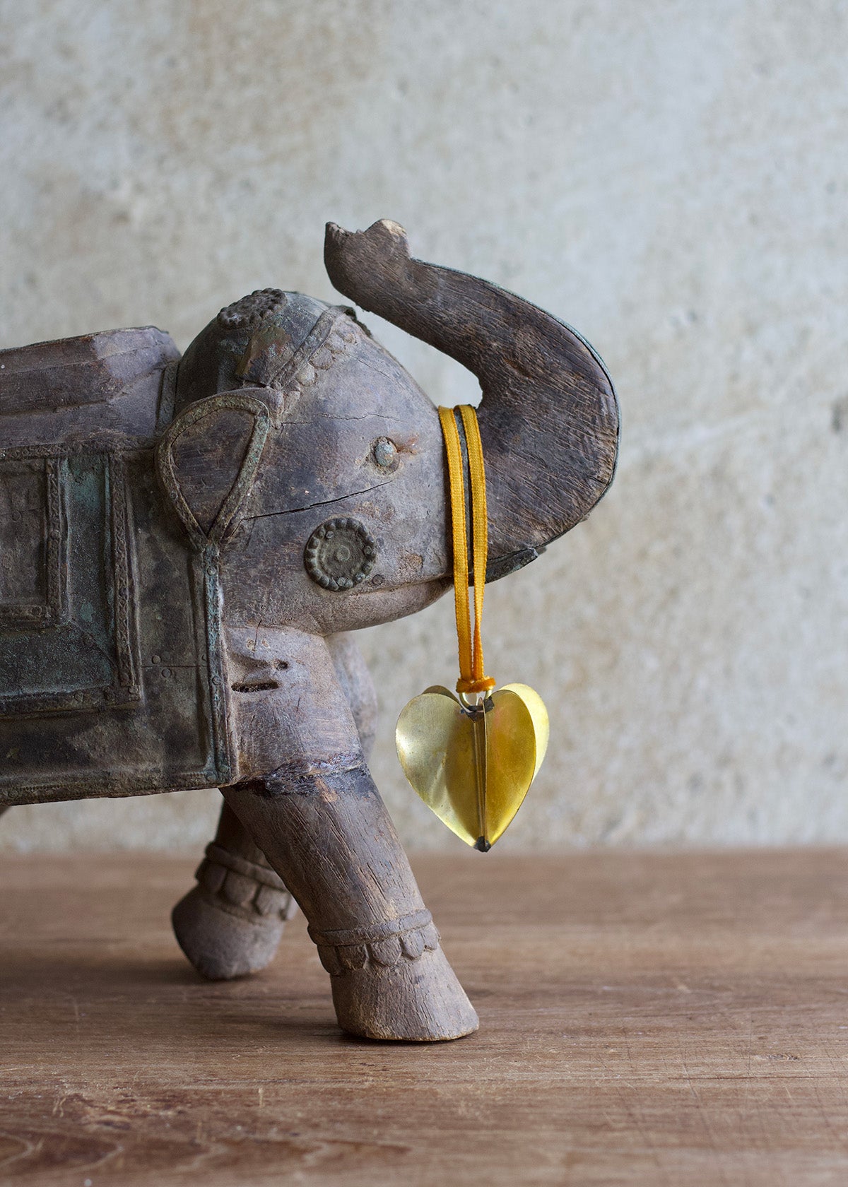 Wooden elephant figurine with a heart-shaped object on a wooden surface