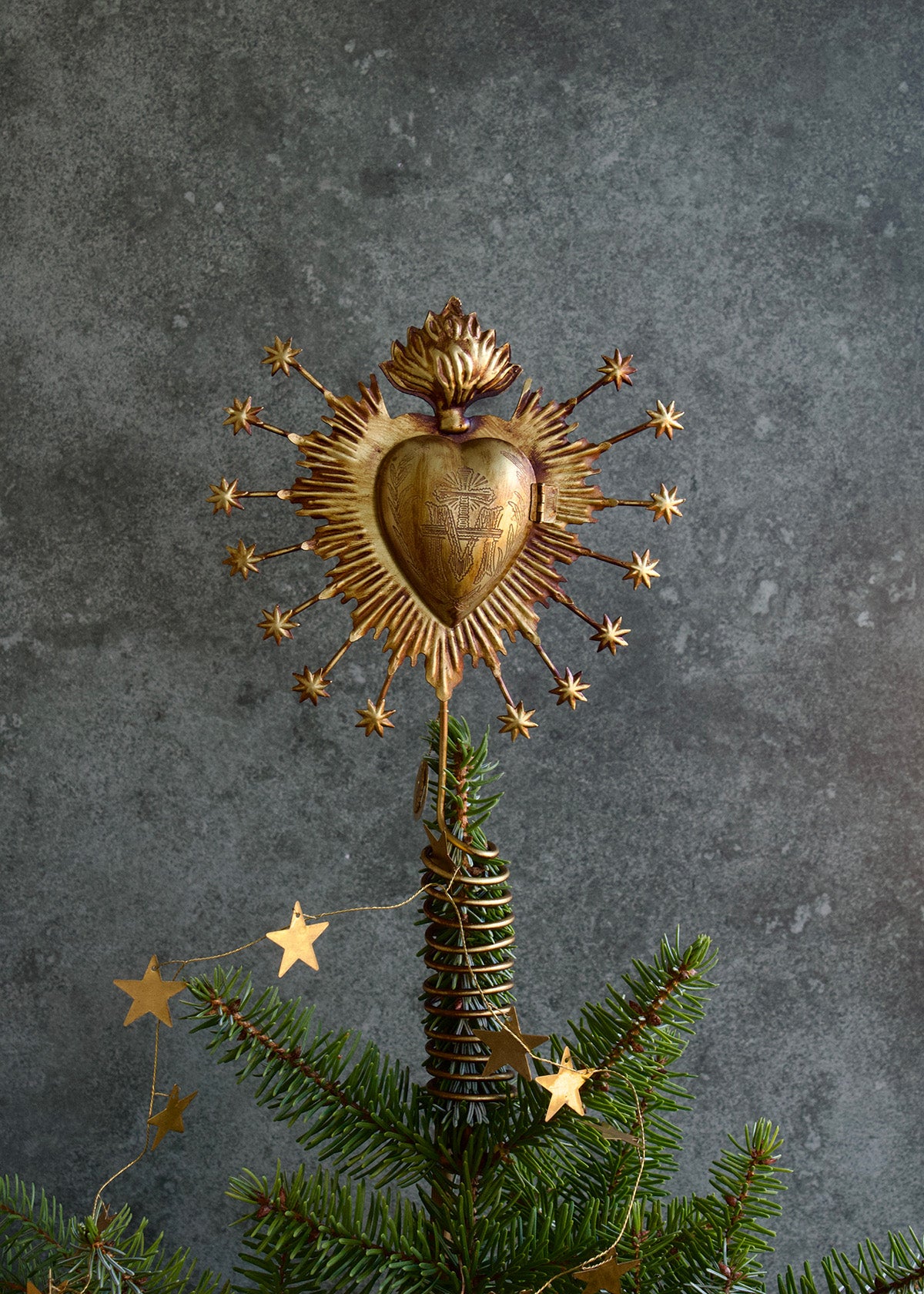 Decorative gold heart with star accents on a Christmas tree against a gray background
