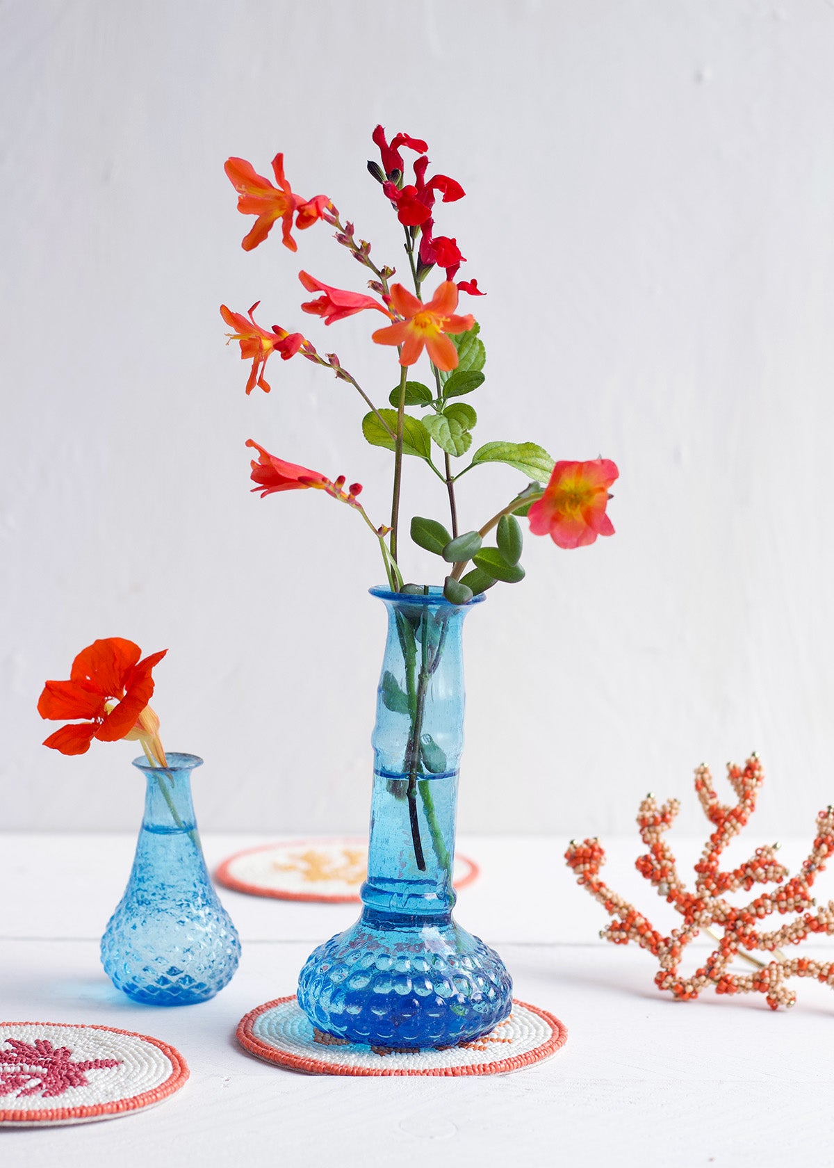Blue textured vase with red flowers on a white background
