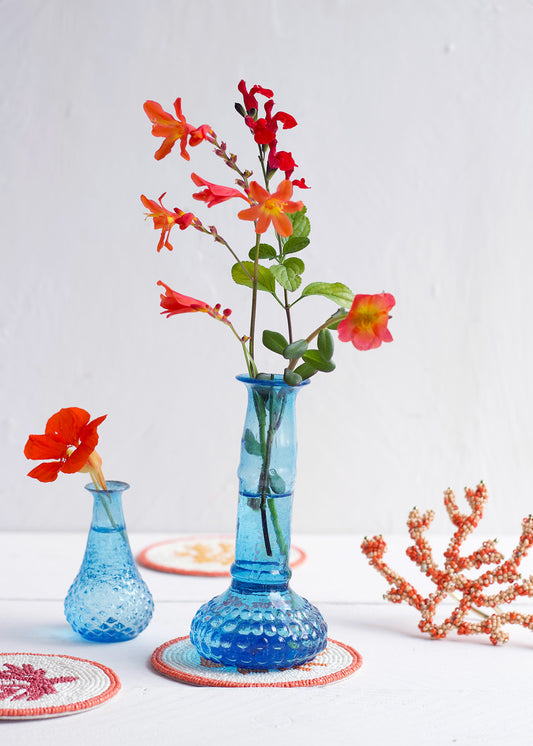 Blue textured vase with red flowers on a white background