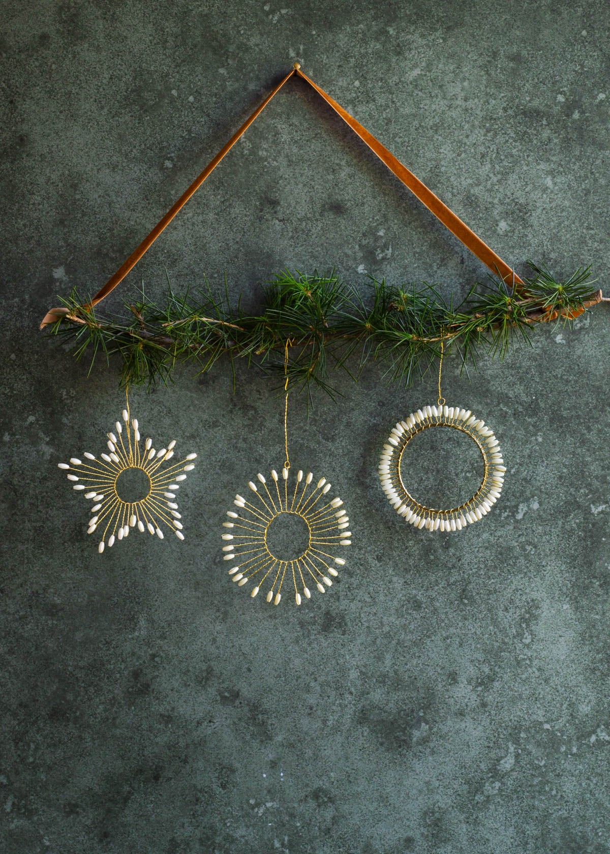 Decorative hanging ornaments with greenery on a textured dark surface
