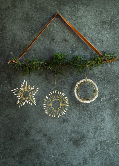 Decorative hanging ornaments with greenery on a textured dark surface