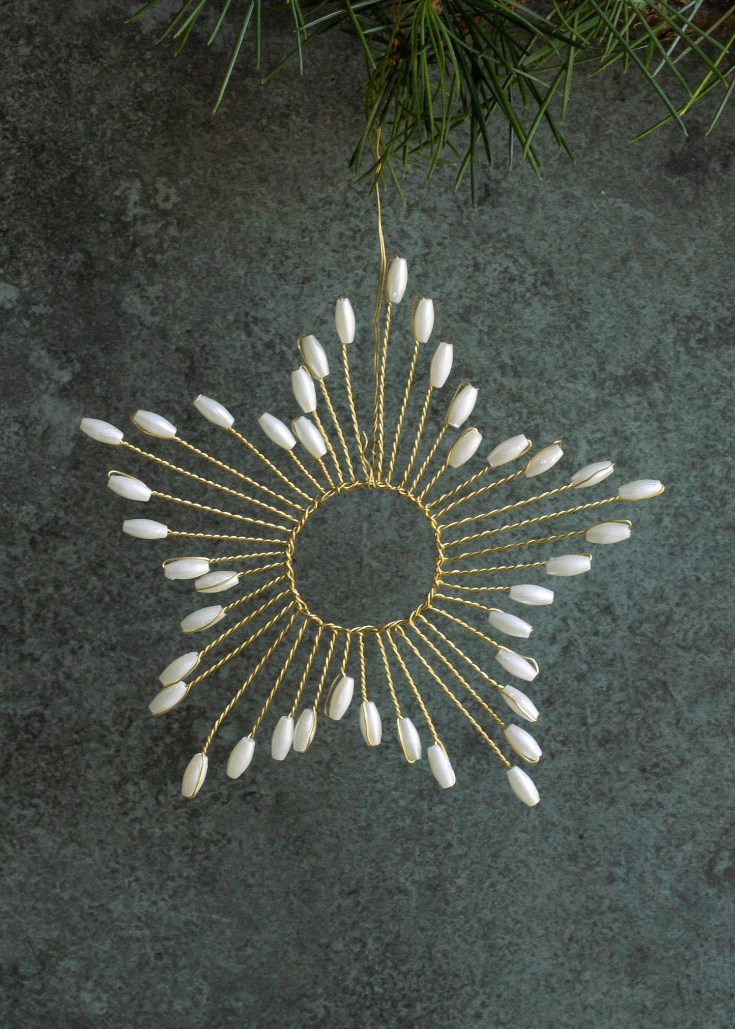 Decorative sun-shaped ornament with white beads on a dark textured background