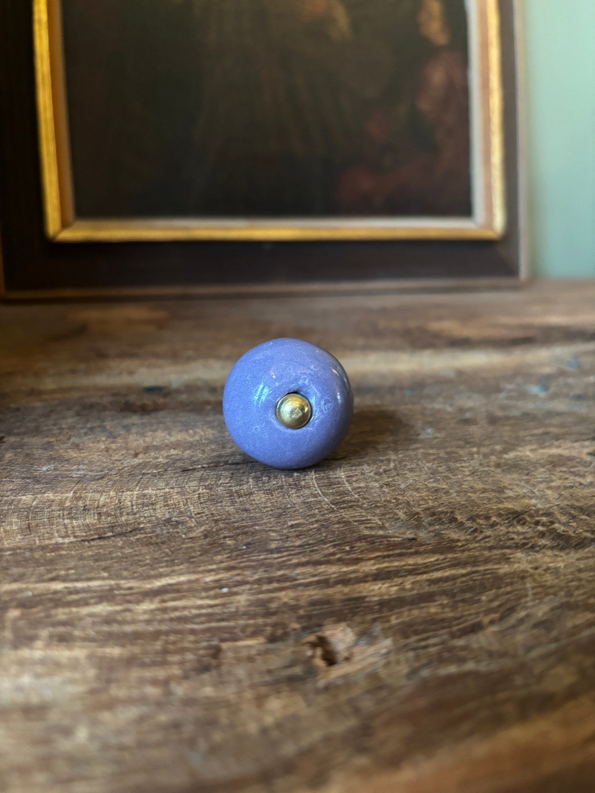 Blue knob on a wooden door with a framed picture in the background