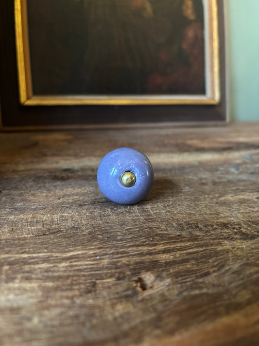 Blue knob on a wooden door with a framed picture in the background