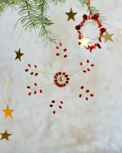 Decorative string with red and gold stars hanging against a neutral background