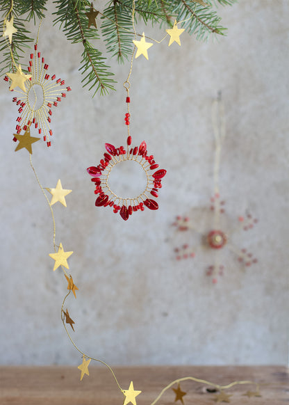 Decorative string lights with red bead accents and gold stars on a neutral background