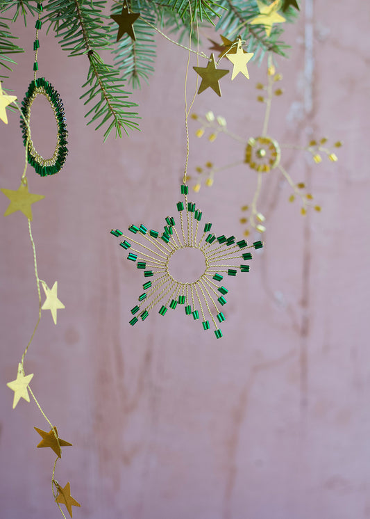 Decorative hanging stars with green beads on a pink background