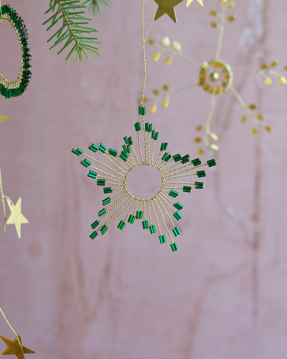 Decorative hanging stars and green circular ornaments on a pink background
