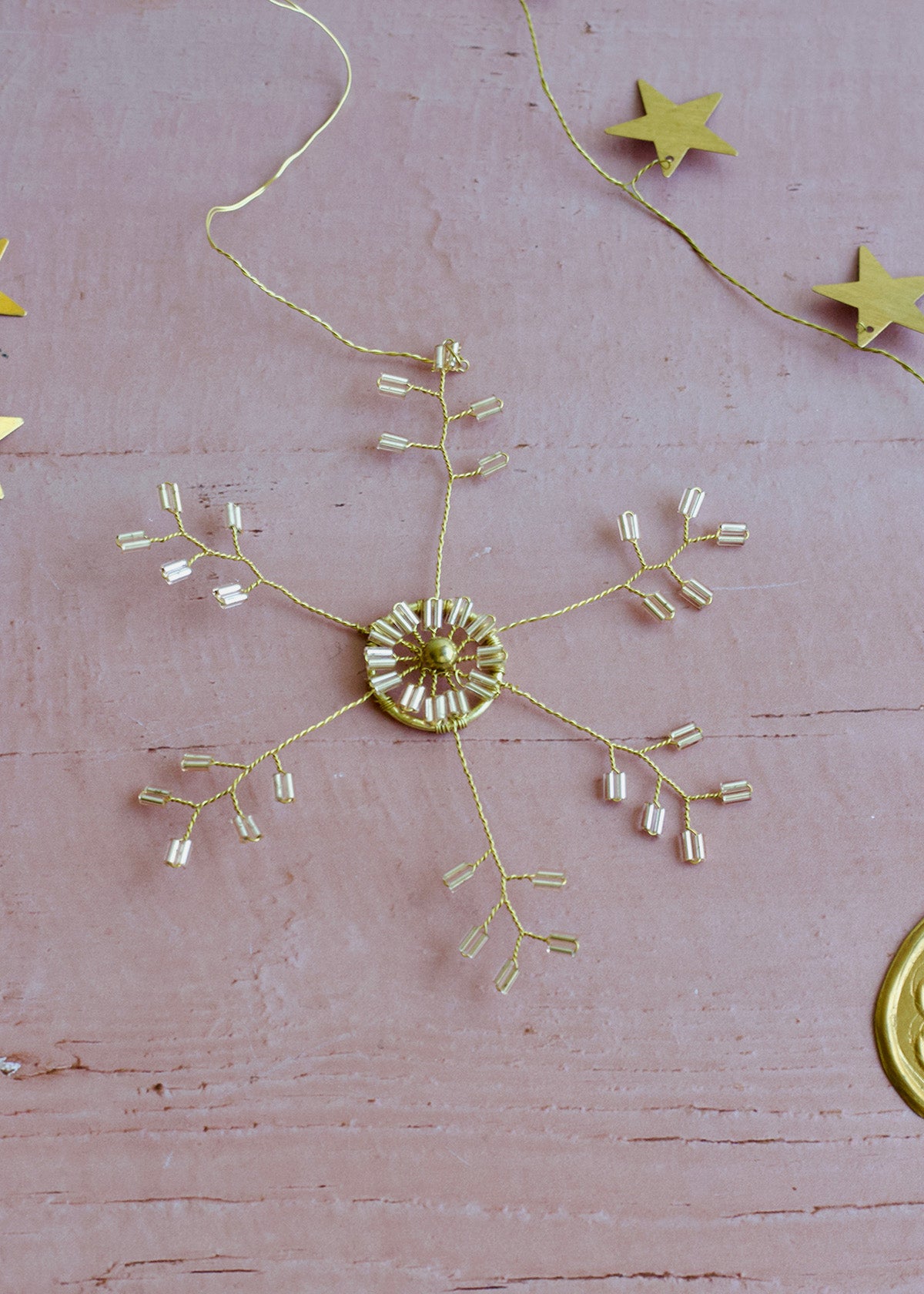 Gold decorative snowflake on a pink surface