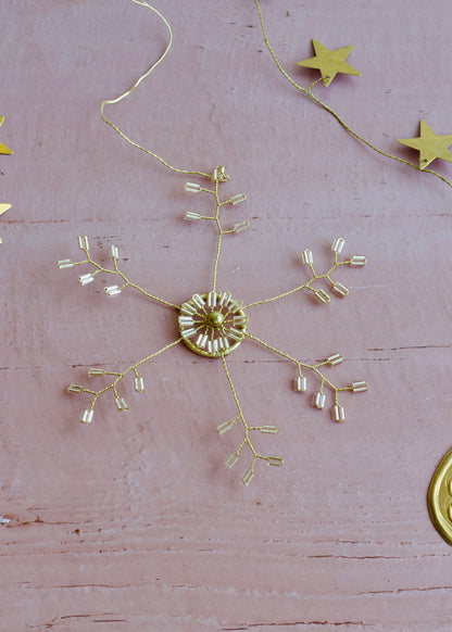 Gold decorative snowflake on a pink surface