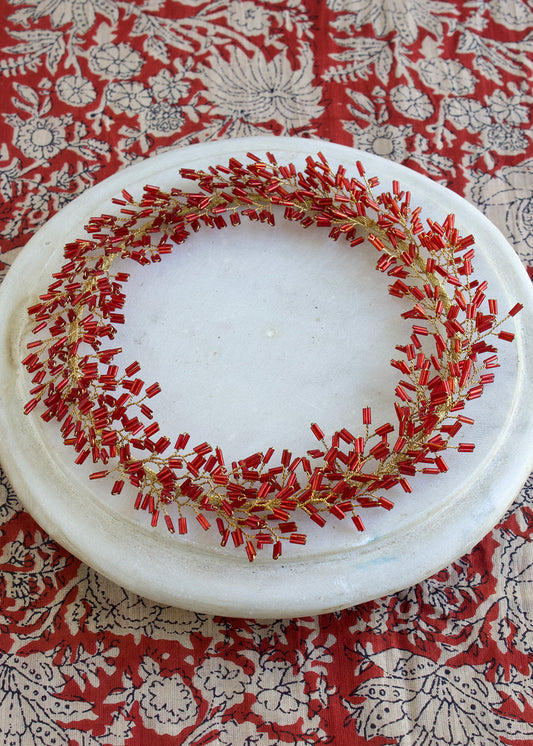 Decorative wreath with red and gold elements on a white plate against a patterned red and white background