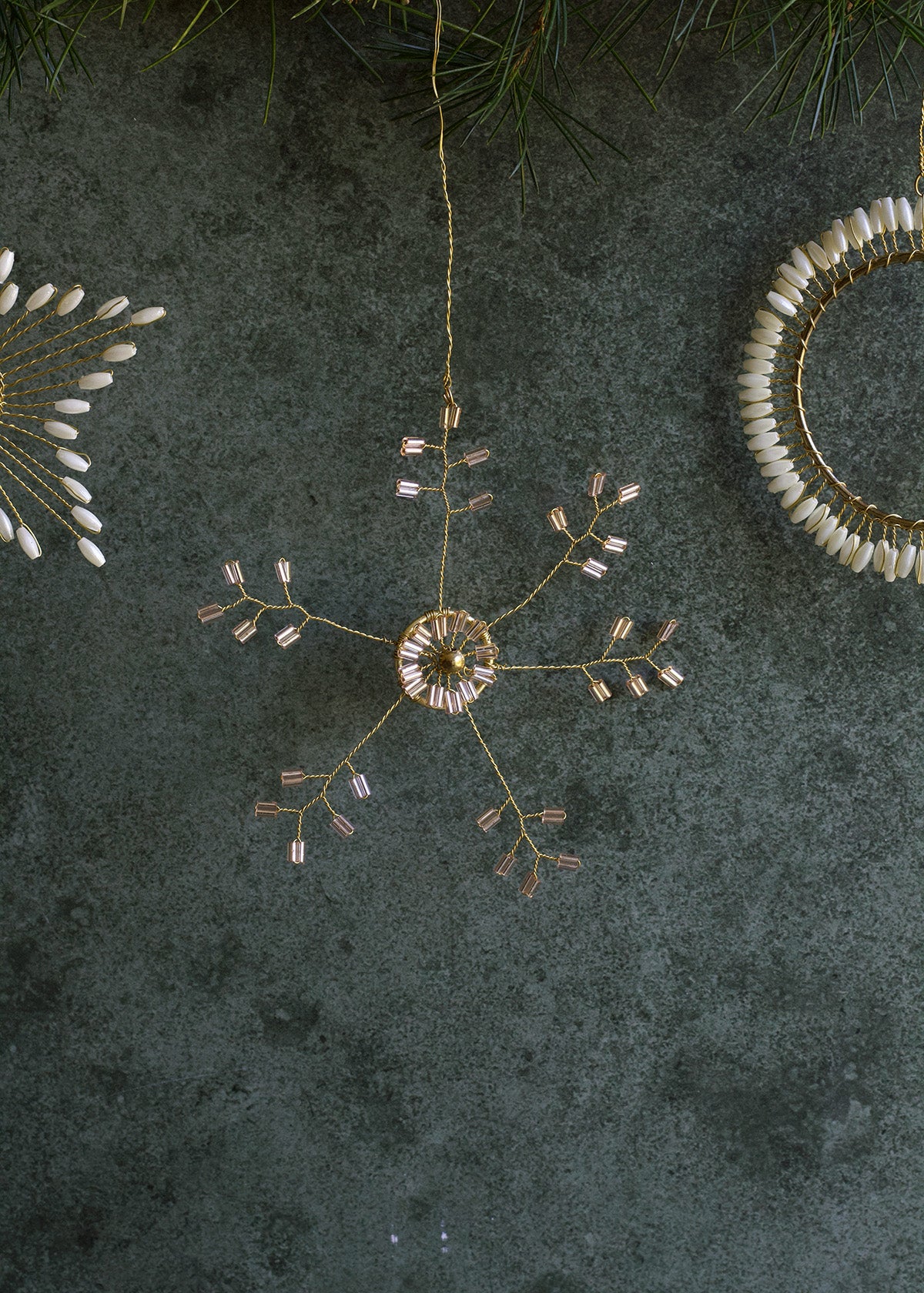 Decorative hanging ornament with gold and white elements on a dark textured surface.