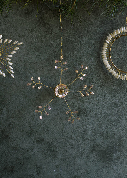 Decorative hanging ornament with gold and white elements on a dark textured surface.