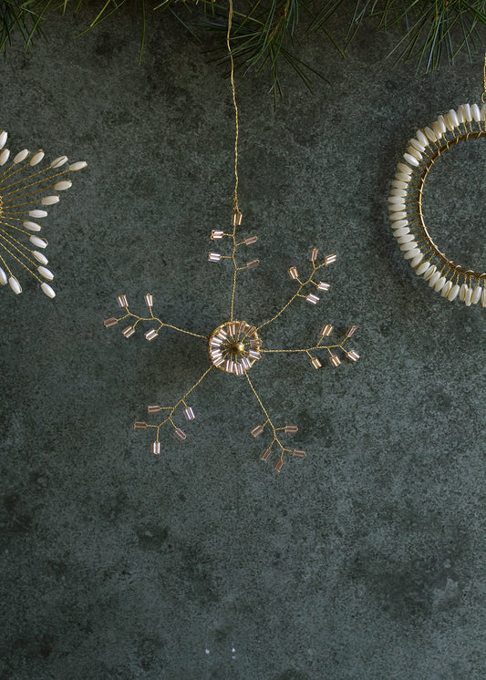 Decorative hanging ornament with gold and white elements on a dark textured surface.