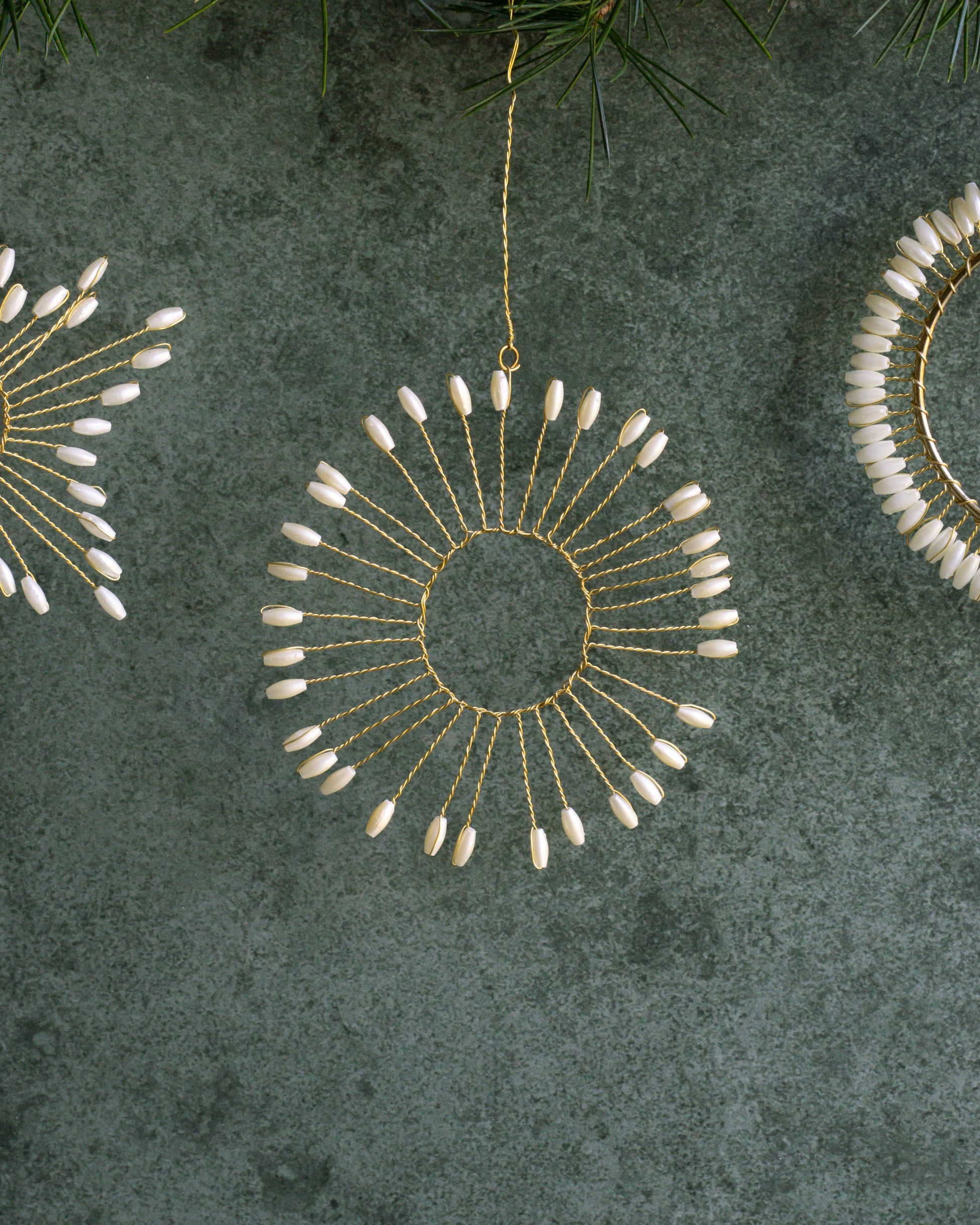 Decorative circular ornaments with bead details on a textured green surface.