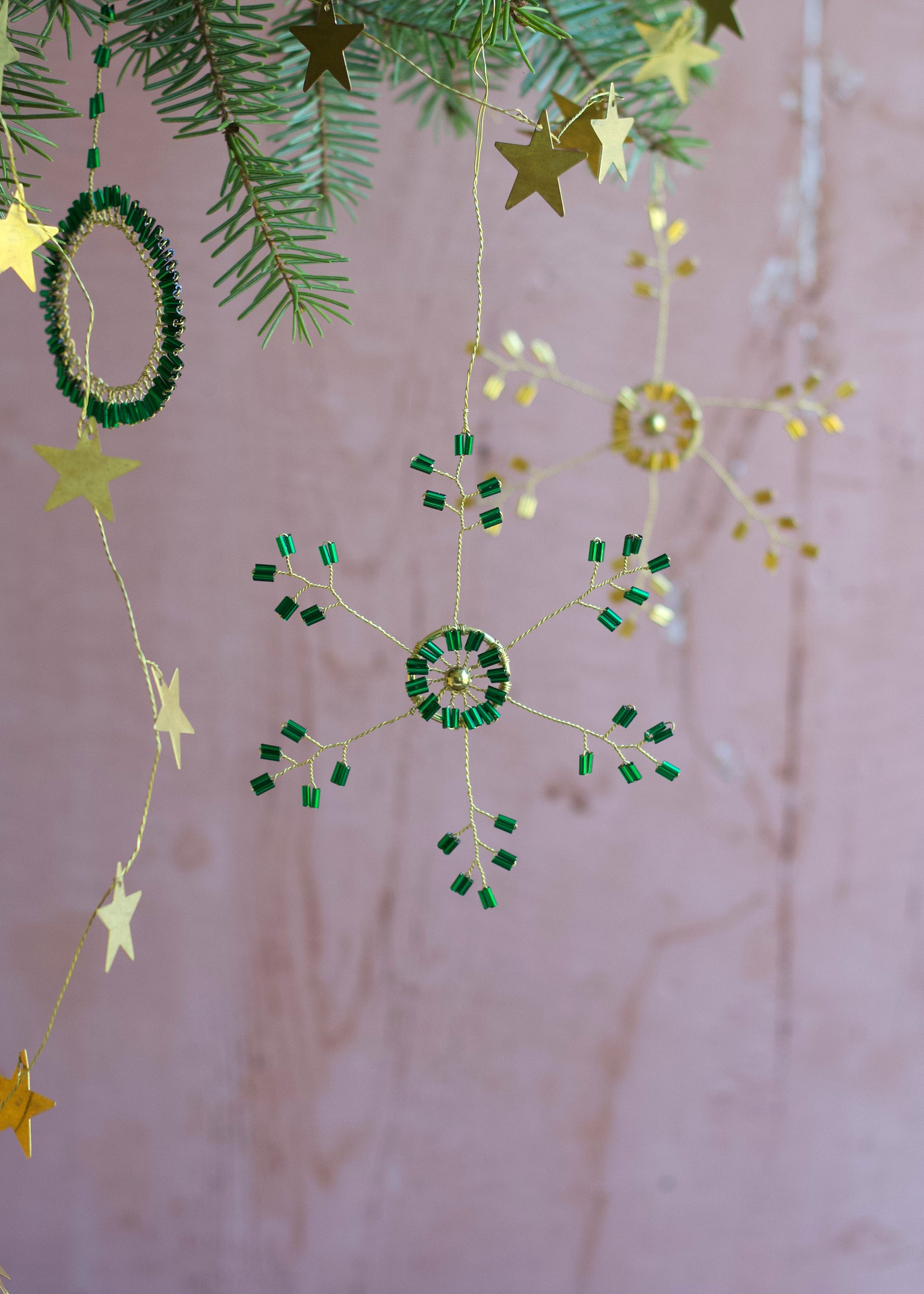 Decorative string with stars and green circular ornaments on a pink background