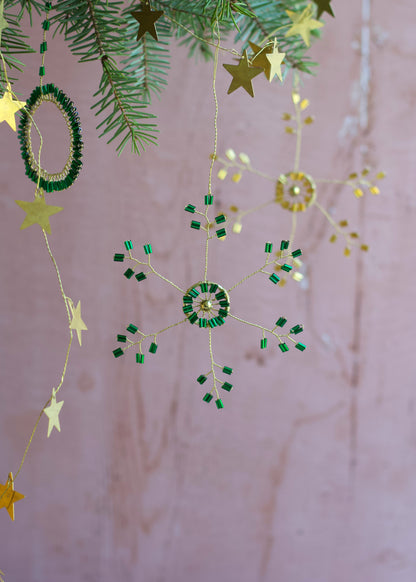 Decorative string with stars and green circular ornaments on a pink background