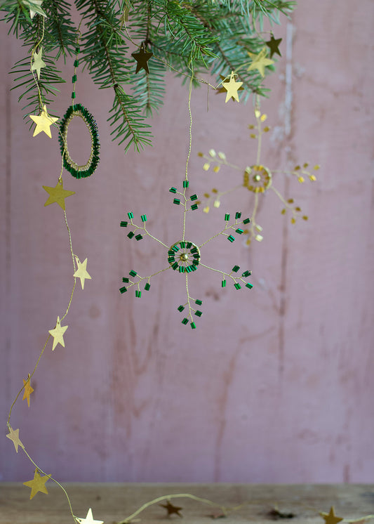 Decorative string with stars and green beads hanging against a pink background