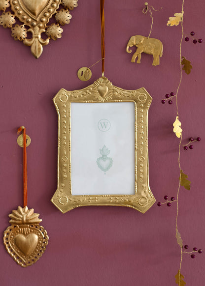 Decorative gold frame with heart and elephant designs on a purple wall.