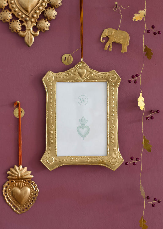 Decorative gold frame with heart and elephant designs on a purple wall.