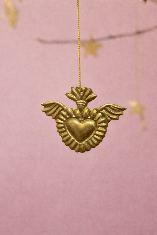 Gold heart-shaped pendant with wings on a pink background