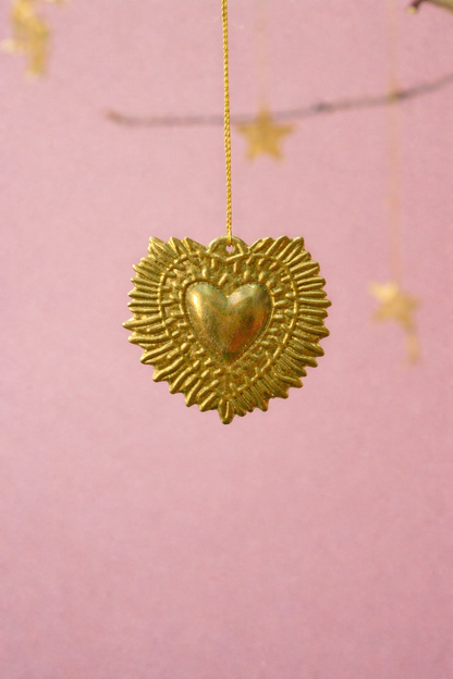 Gold heart-shaped pendant with star details on a pink background