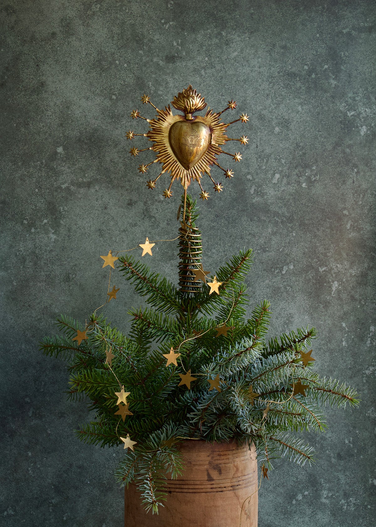 Decorative Christmas tree with gold star decorations and a heart-shaped gold ornament against a dark background.