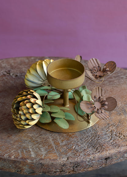Decorative gold candle holder with floral designs on a wooden surface