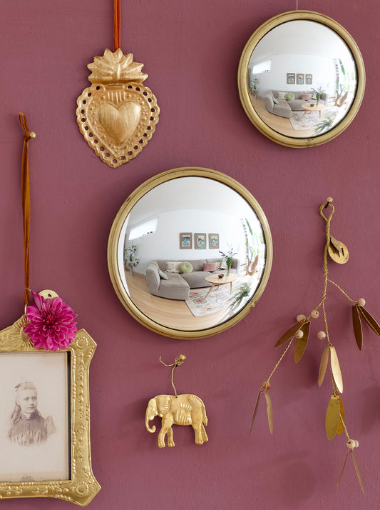 Decorative wall with gold mirrors, framed photo, and other ornaments on a purple wall.