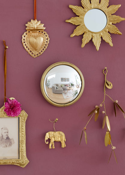 Decorative wall with gold mirrors, frames, and ornaments on a purple wall.