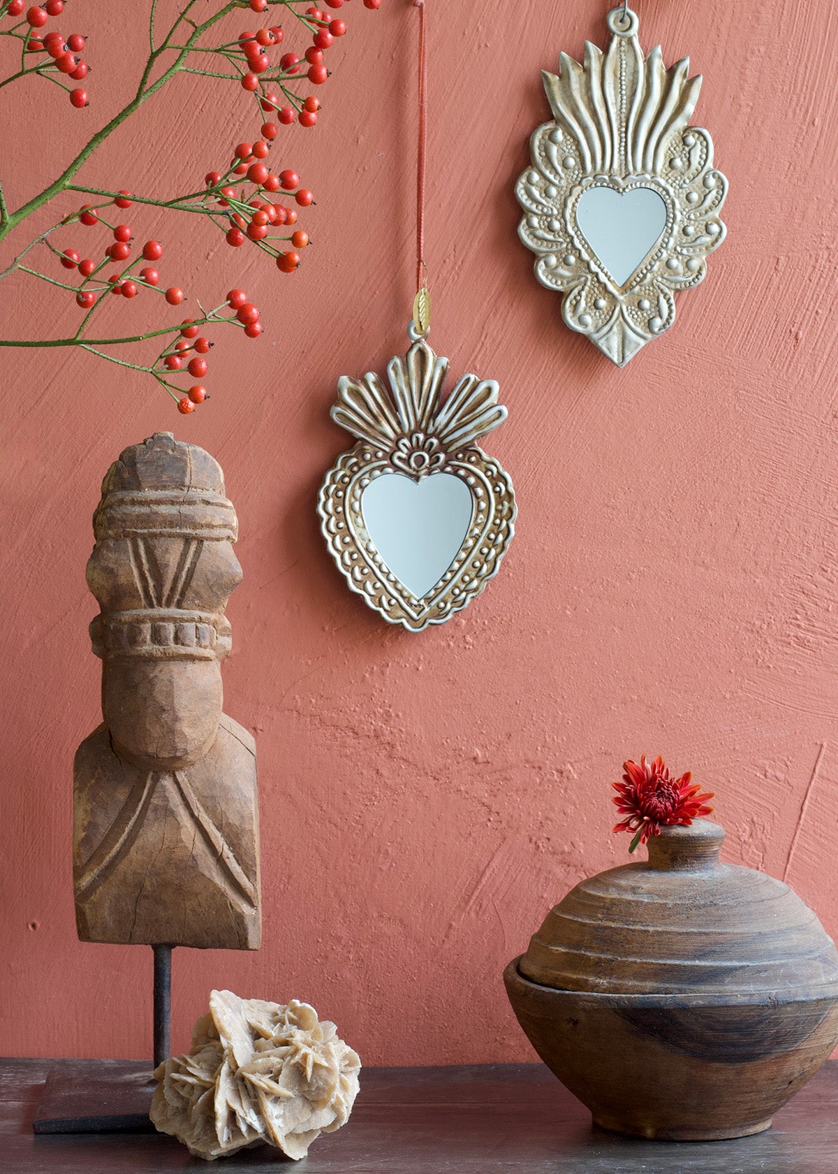 Decorative mirrors and wooden sculptures on a pink wall