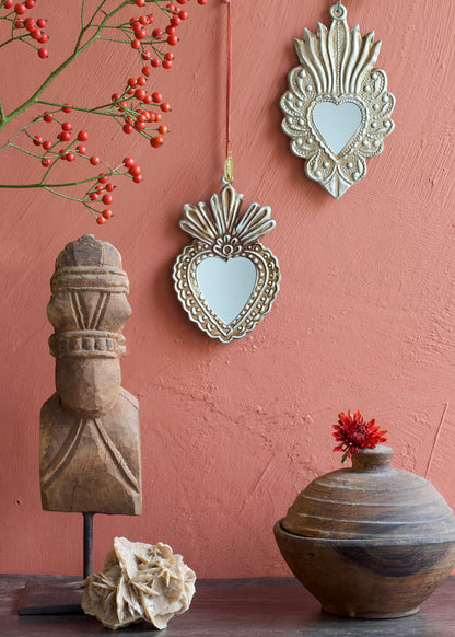 Decorative mirrors and wooden sculptures on a pink wall
