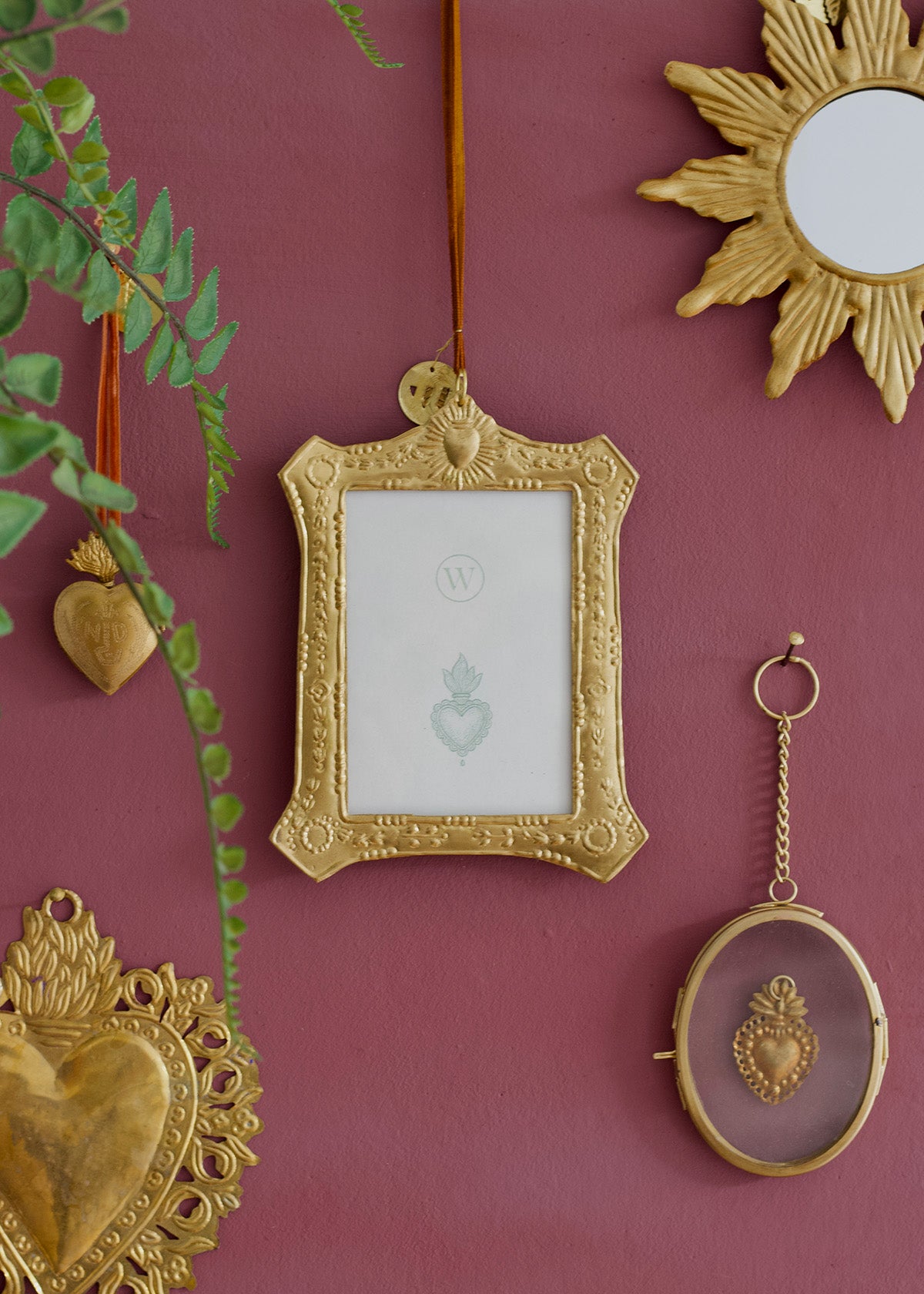 Decorative gold frames and heart-shaped objects on a pink wall