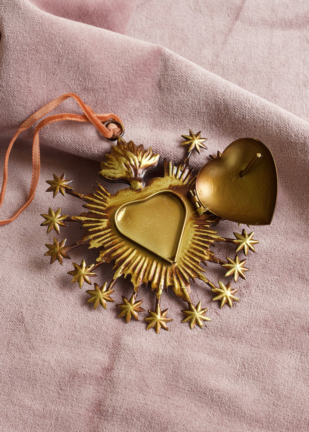 Gold heart-shaped decorative item with stars on a pink fabric background