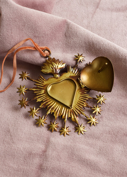 Gold heart-shaped decorative item with stars on a pink fabric background