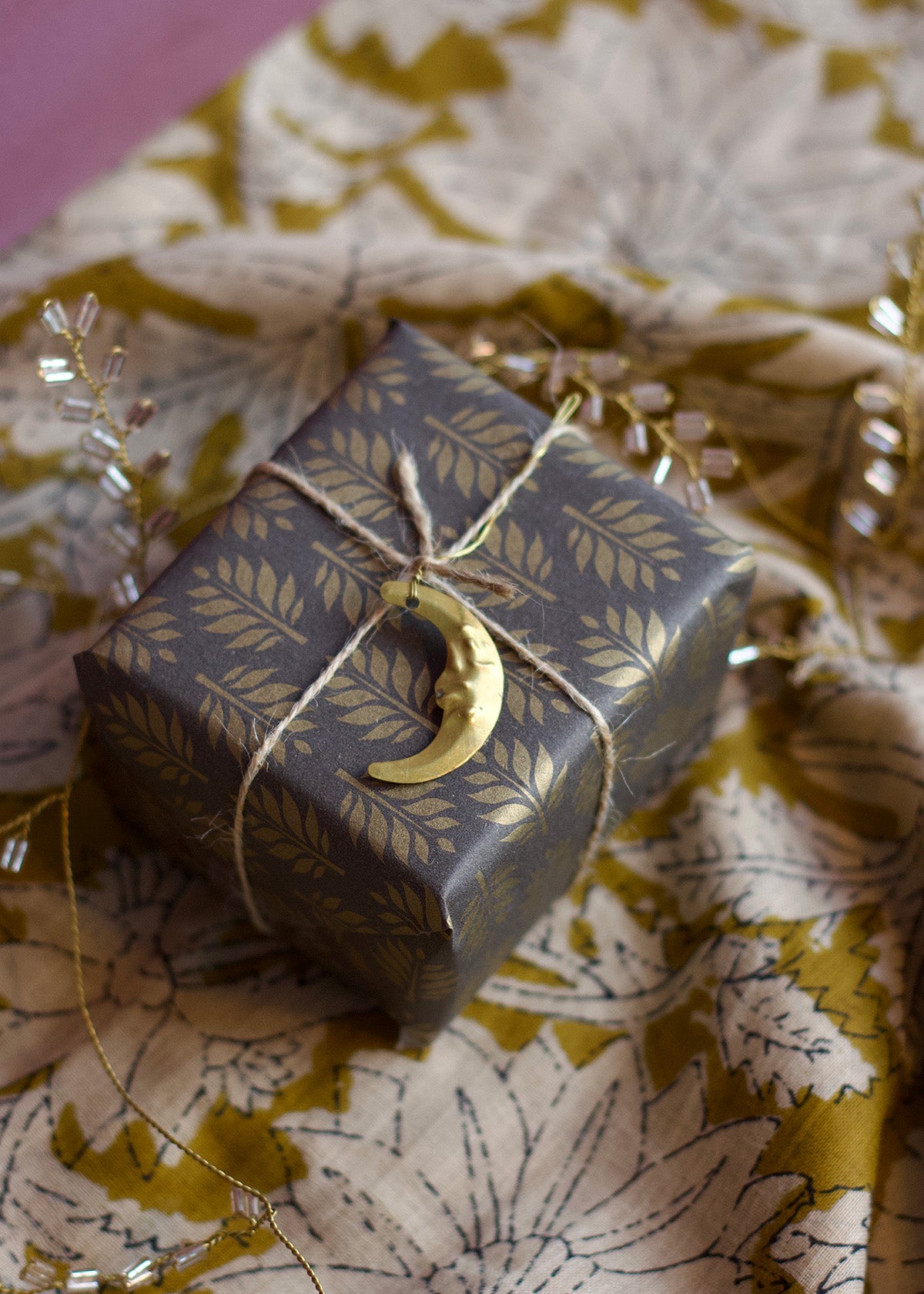 Gift box with gold crescent moon charm on floral fabric