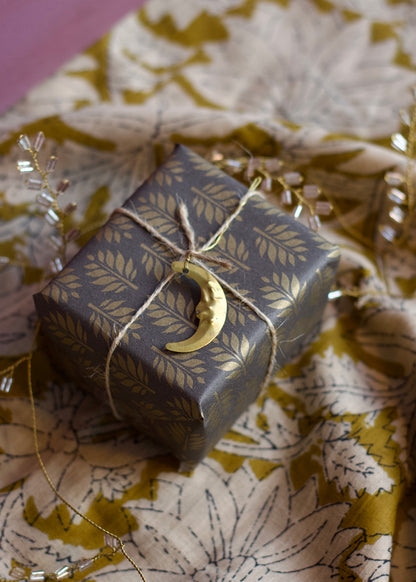 Gift box with gold crescent moon charm on floral fabric
